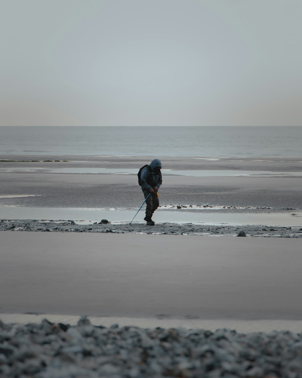 homem na jaqueta preta que anda na praia durante o dia