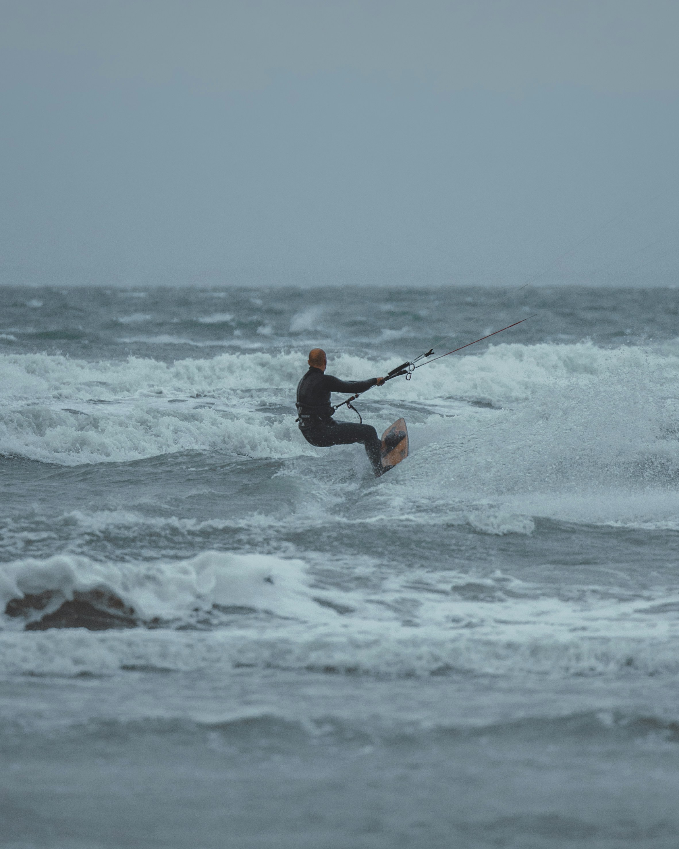 hombre en traje de neopreno negro surfeando en las olas del mar durante el día