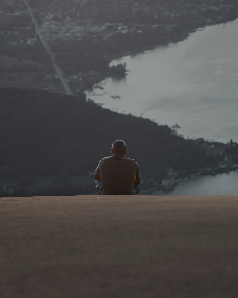 man in black shirt sitting on brown field near green trees during daytime