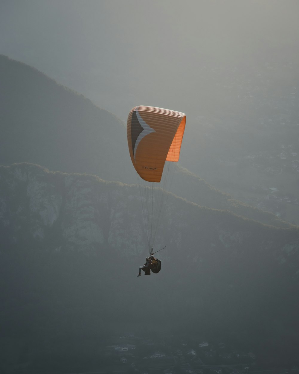 Persona en paracaídas naranja sobre nubes blancas durante el día