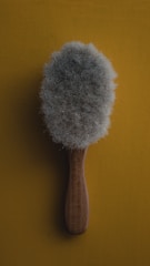 Close-up of a soft brush gently cleaning a colorful rug.