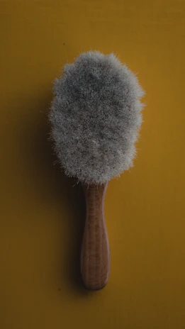 Close-up of a premium angled brush with vibrant orange bristles against a deep navy background.