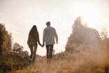 Couple walking hand in hand along a sunlit garden path
