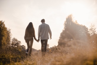 A serene park scene with a couple walking hand in hand during golden hour.
