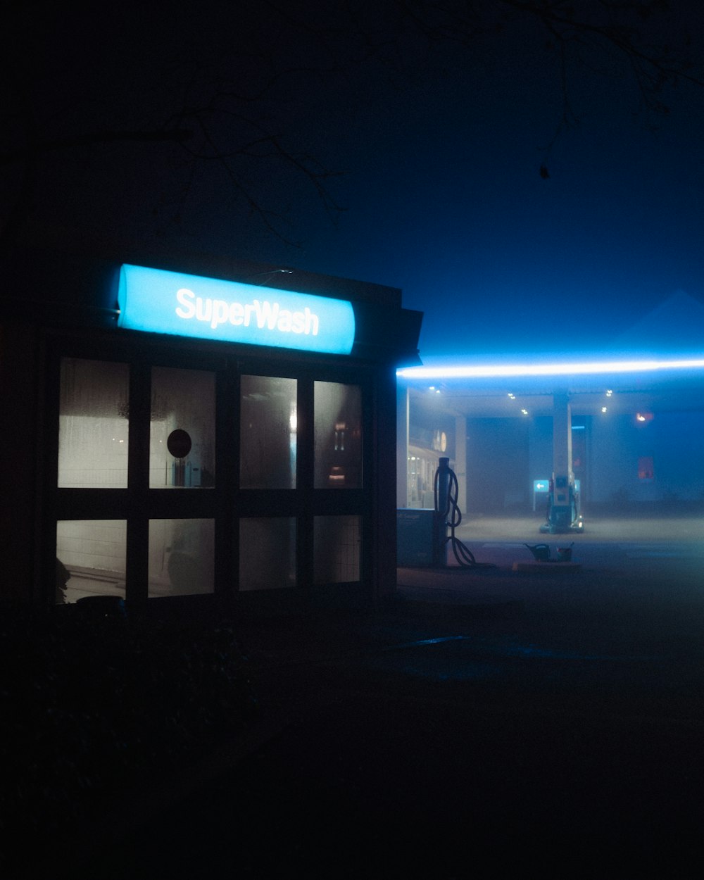man in black jacket standing near blue and white store during night time