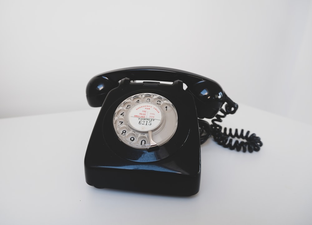 téléphone à cadran noir sur surface blanche