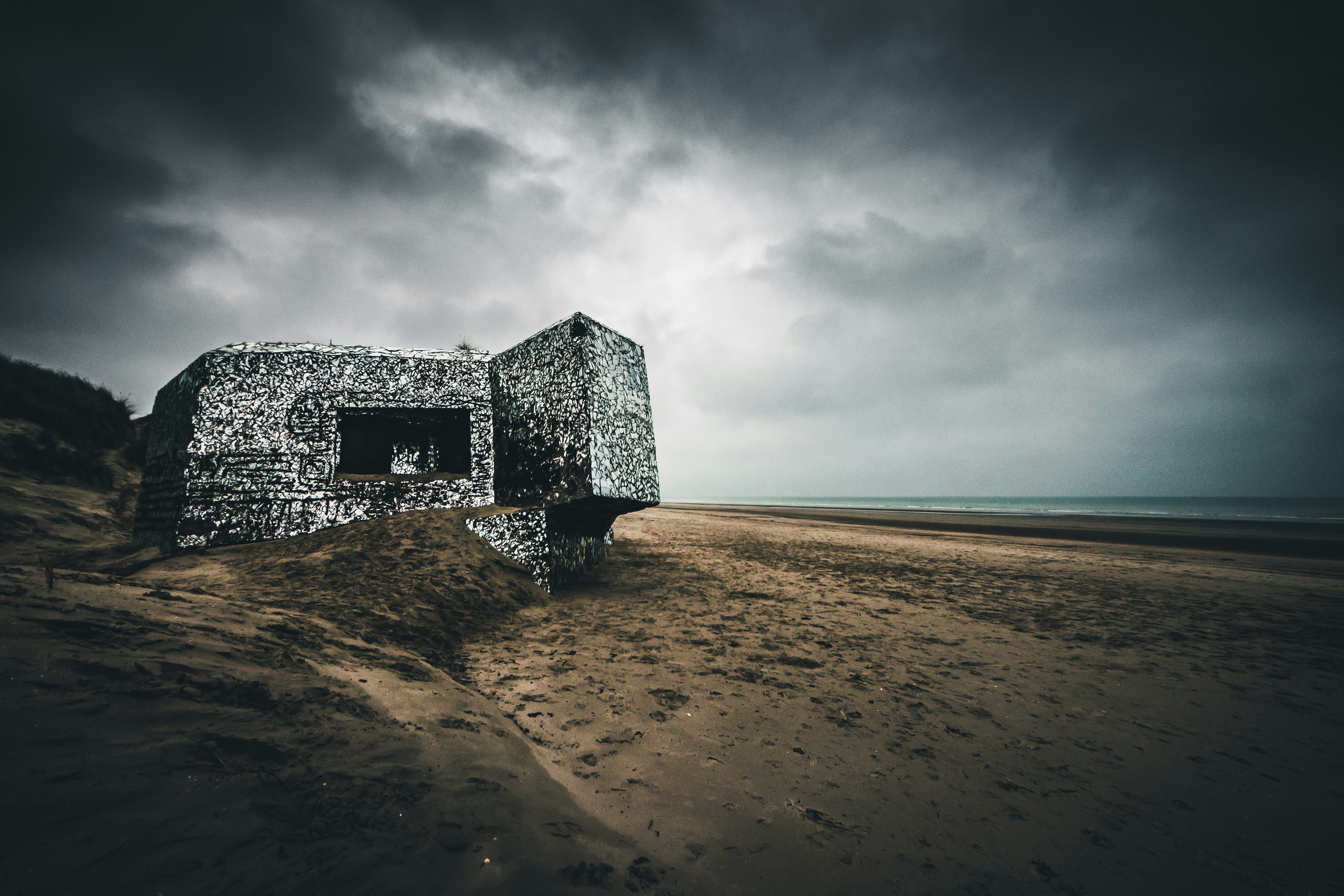 gray concrete building on brown sand near sea under gray clouds during daytime