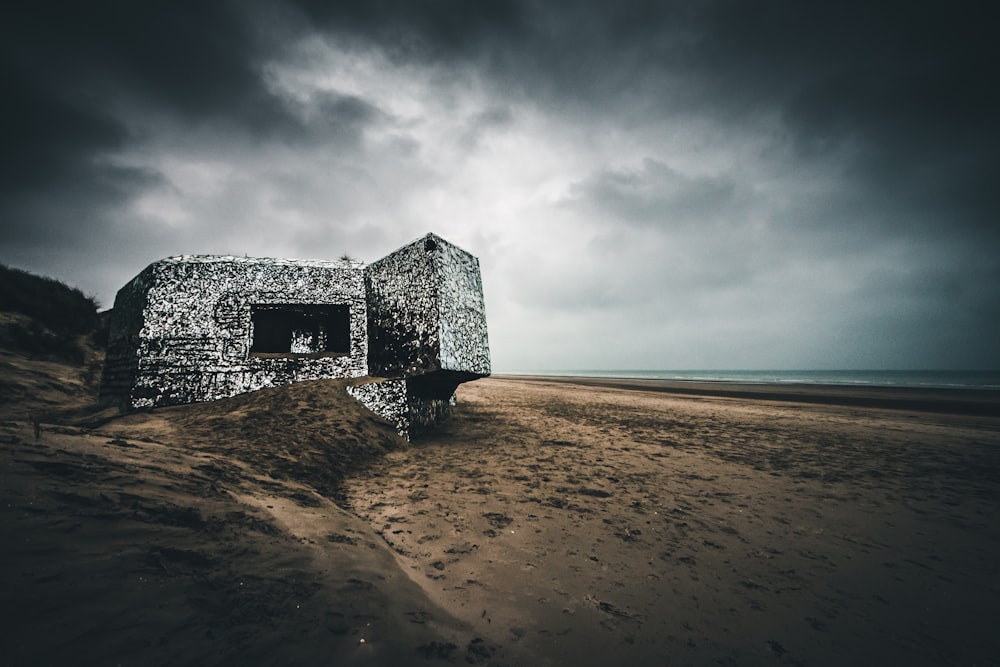 gray concrete building on brown sand near sea under gray clouds during daytime