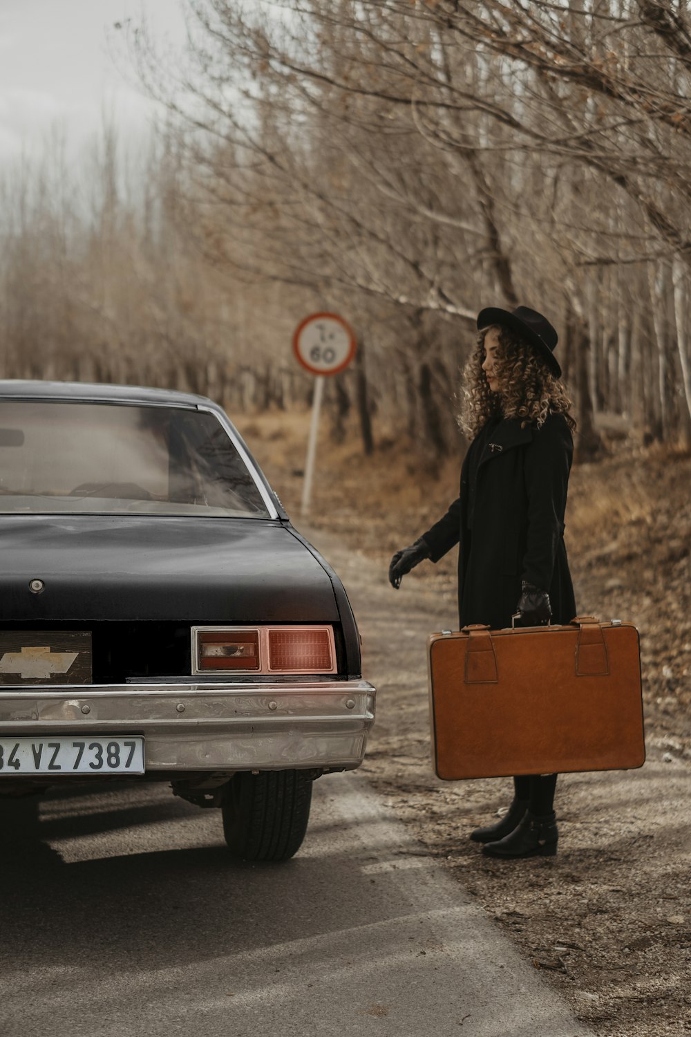 woman in black dress standing beside red car during daytime