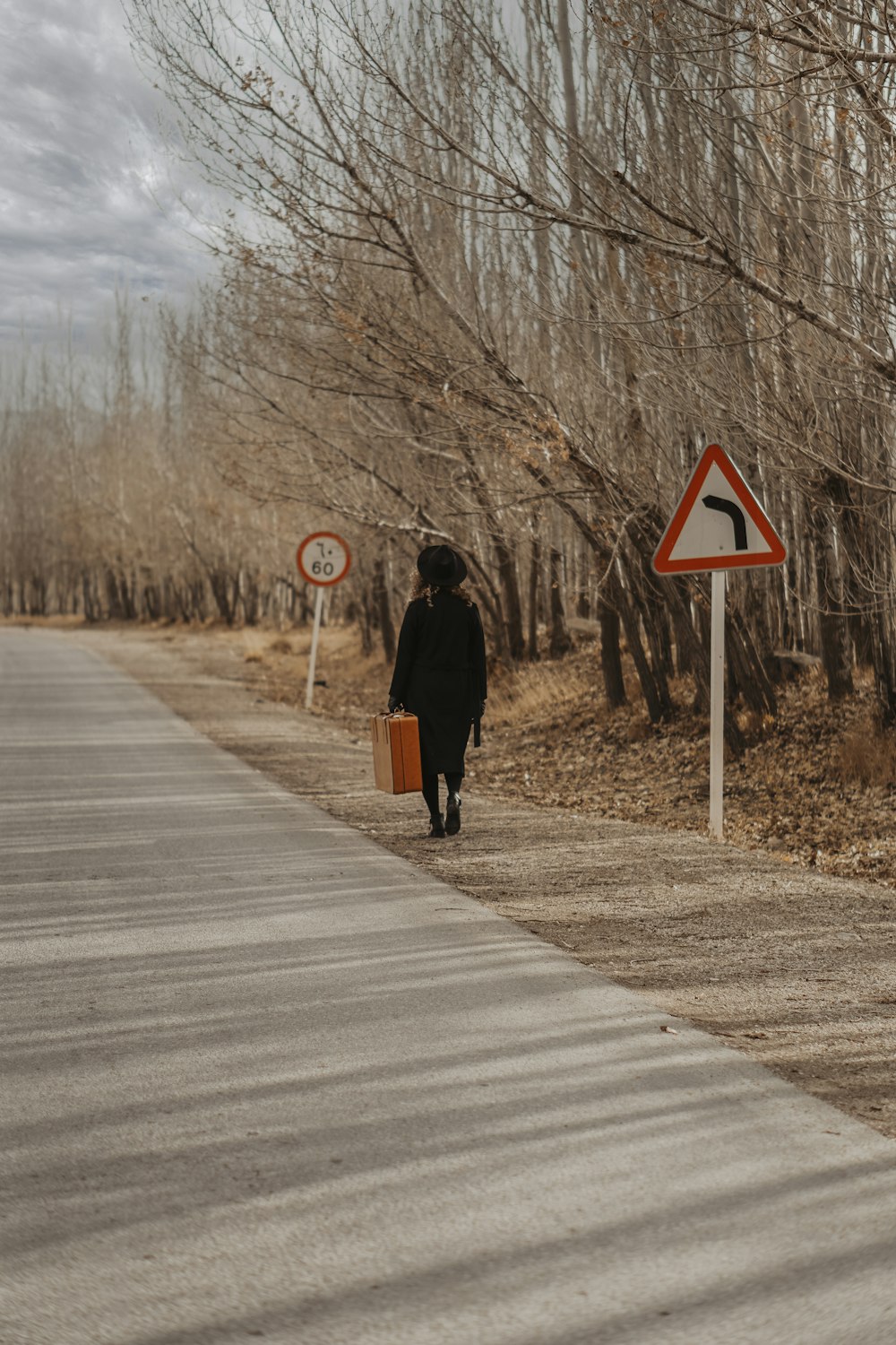 woman in black coat walking on gray concrete road during daytime