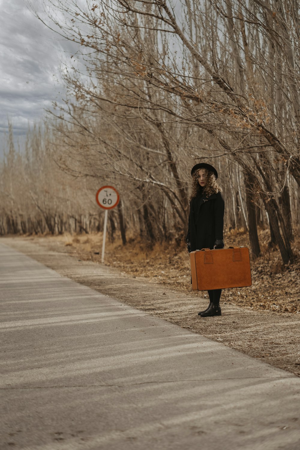 woman in black jacket sitting on brown wooden bench