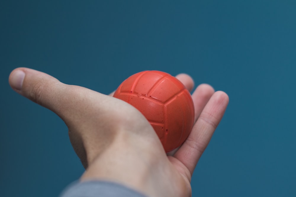 person holding orange ball under blue sky during daytime