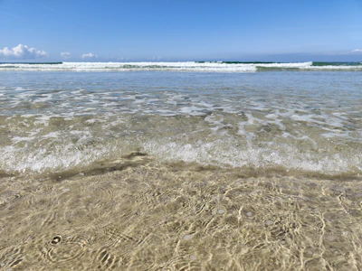 Close-up of sparkling ocean waves rolling onto a pristine white sand beach.
