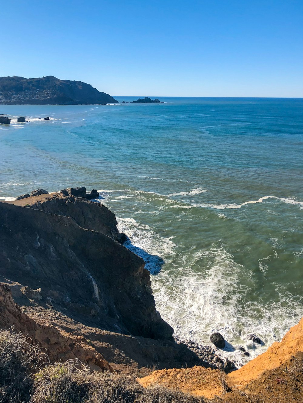 brown rocky mountain beside blue sea during daytime