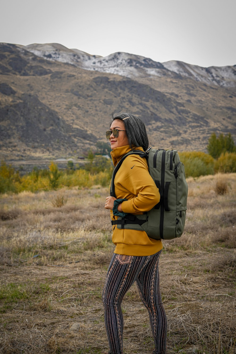 woman in black and white plaid skirt with black backpack standing on green grass field during