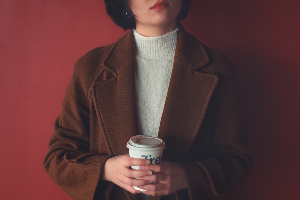 Mujer con abrigo marrón sosteniendo una taza de café marrón