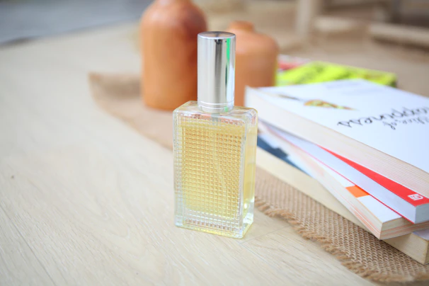 Brightly colored ceramic perfume bottles arranged on a rustic wooden shelf with warm sunlight.