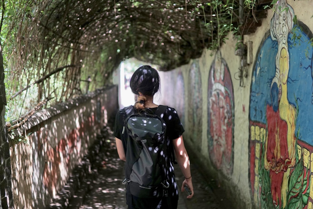 woman in black and white dress standing beside wall with graffiti