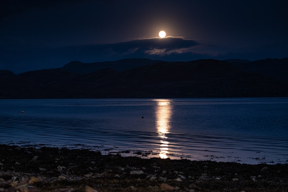 body of water near mountain during night time