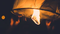 Close-up of hands holding a glowing lantern symbolizing hope and guidance on a dark path.