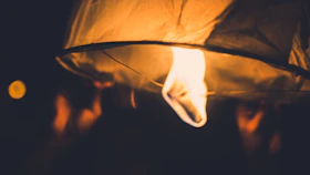 Close-up of hands holding a glowing lantern symbolizing hope and guidance on a dark path.