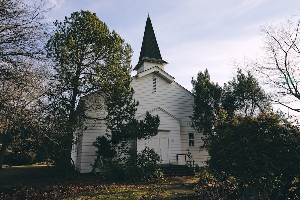 white and black church beside green tree under white clouds during daytime