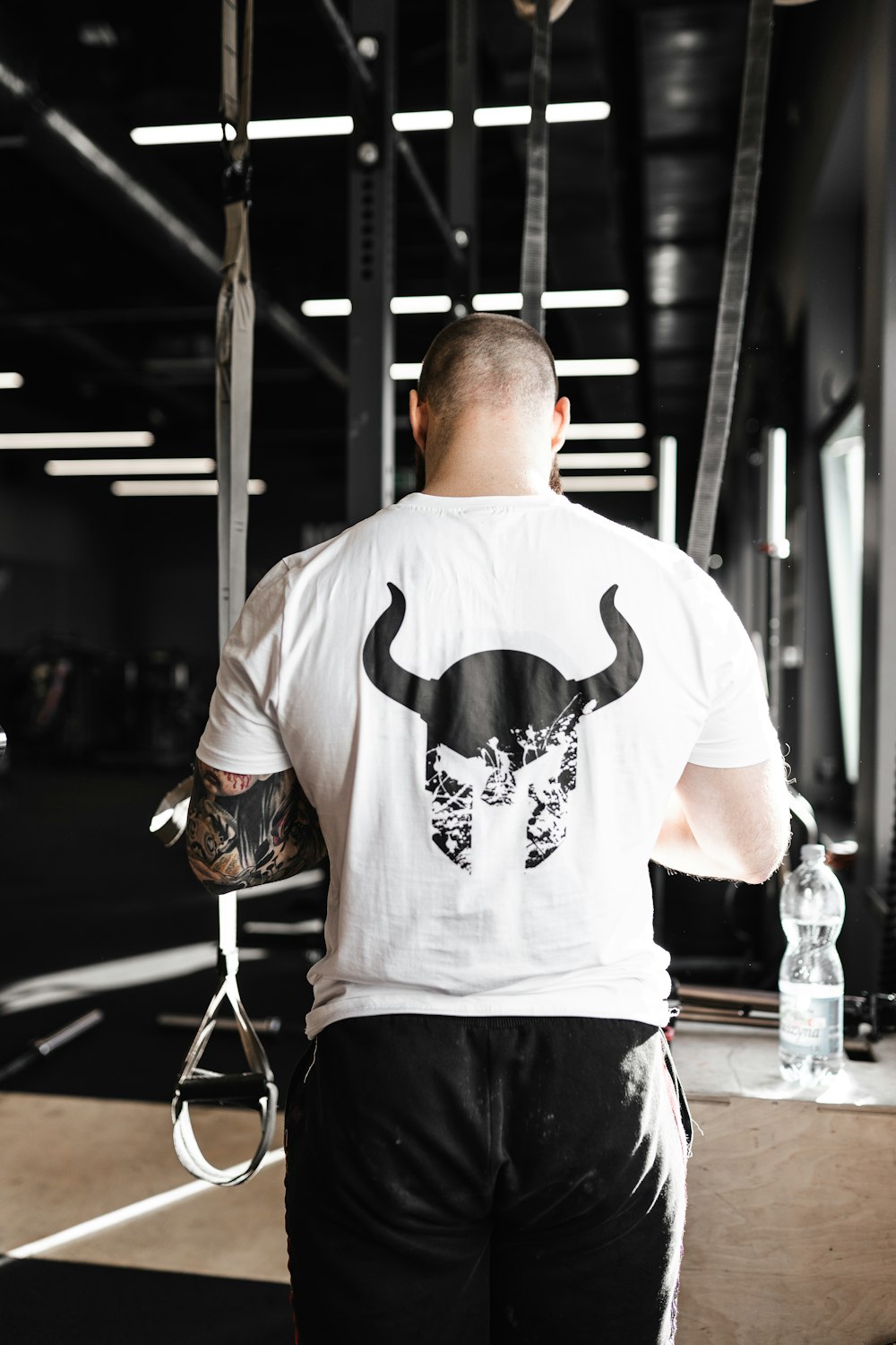 man in white and black crew neck t-shirt and black pants sitting on chair