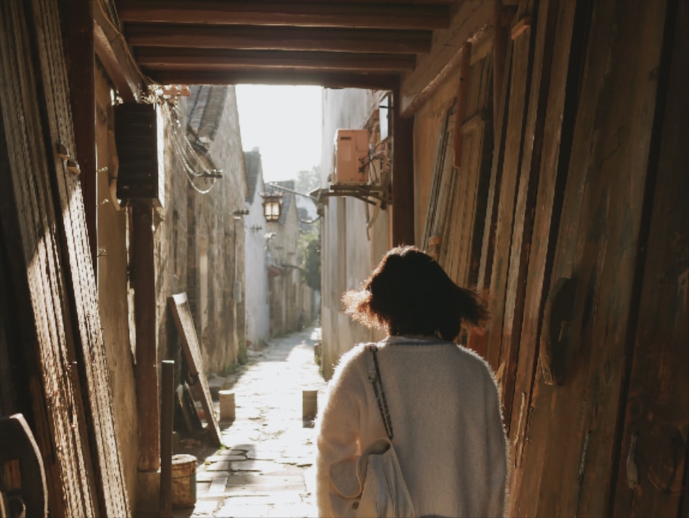 woman in brown coat walking on hallway during daytime