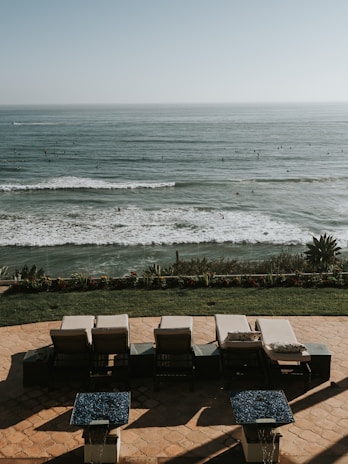 An outdoor terrace with lounge chairs overlooking a sunset.