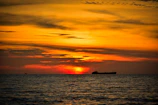 A vibrant sunset over Port Canaveral with a cruise ship silhouetted against the orange sky.
