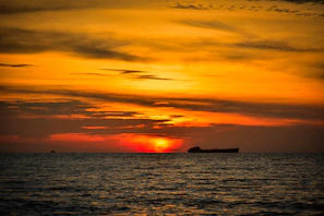 A vibrant sunset over Port Canaveral with a cruise ship silhouetted against the orange sky.