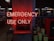 A neon red sign reading 'EMERGENCY USE ONLY' is prominently displayed on a wall. The surrounding environment appears to be dimly lit, with metal barrels labeled 'EMERGENCY' and some industrial-looking equipment in the background. Shelves and display counters are visible in a retail-like setting.
