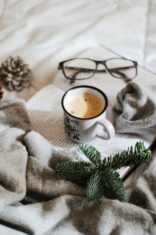 A cozy pair of sloth-themed socks resting on a wooden table beside a steaming cup of coffee.
