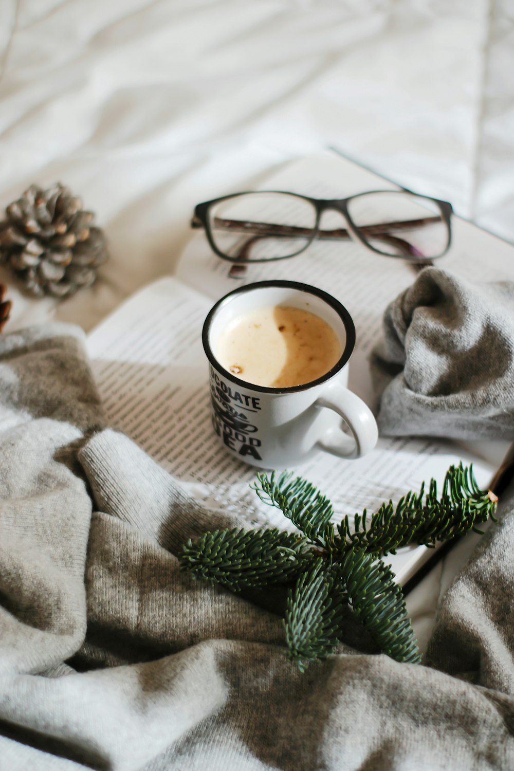 white ceramic mug with coffee on white textile