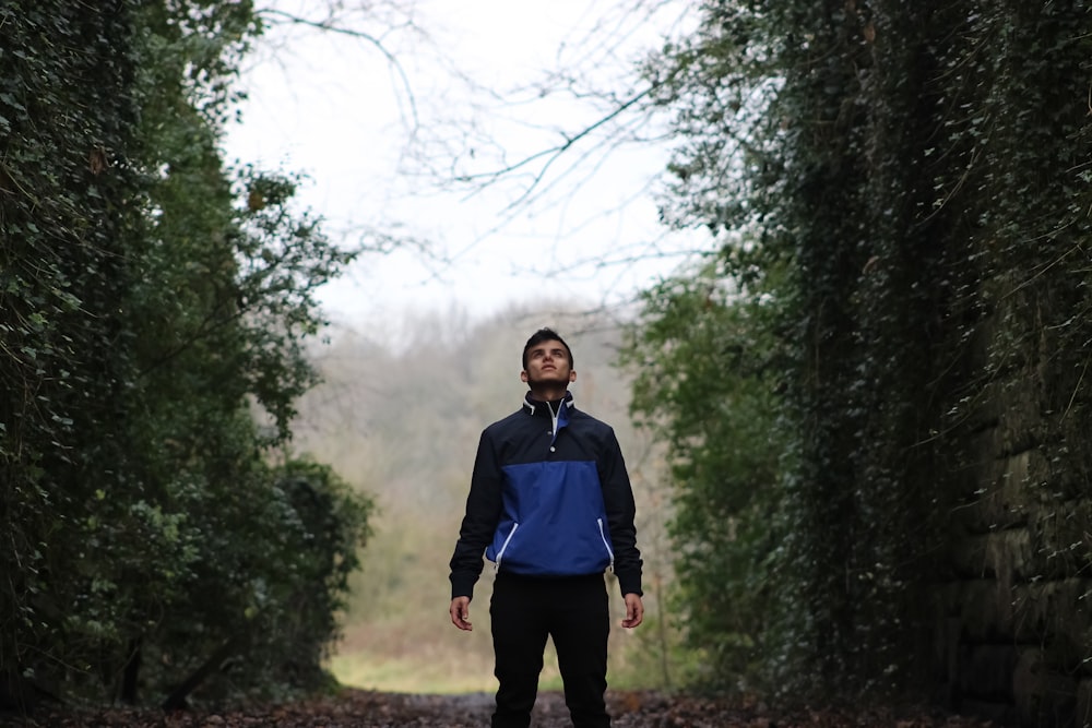 woman in blue jacket standing on forest during daytime