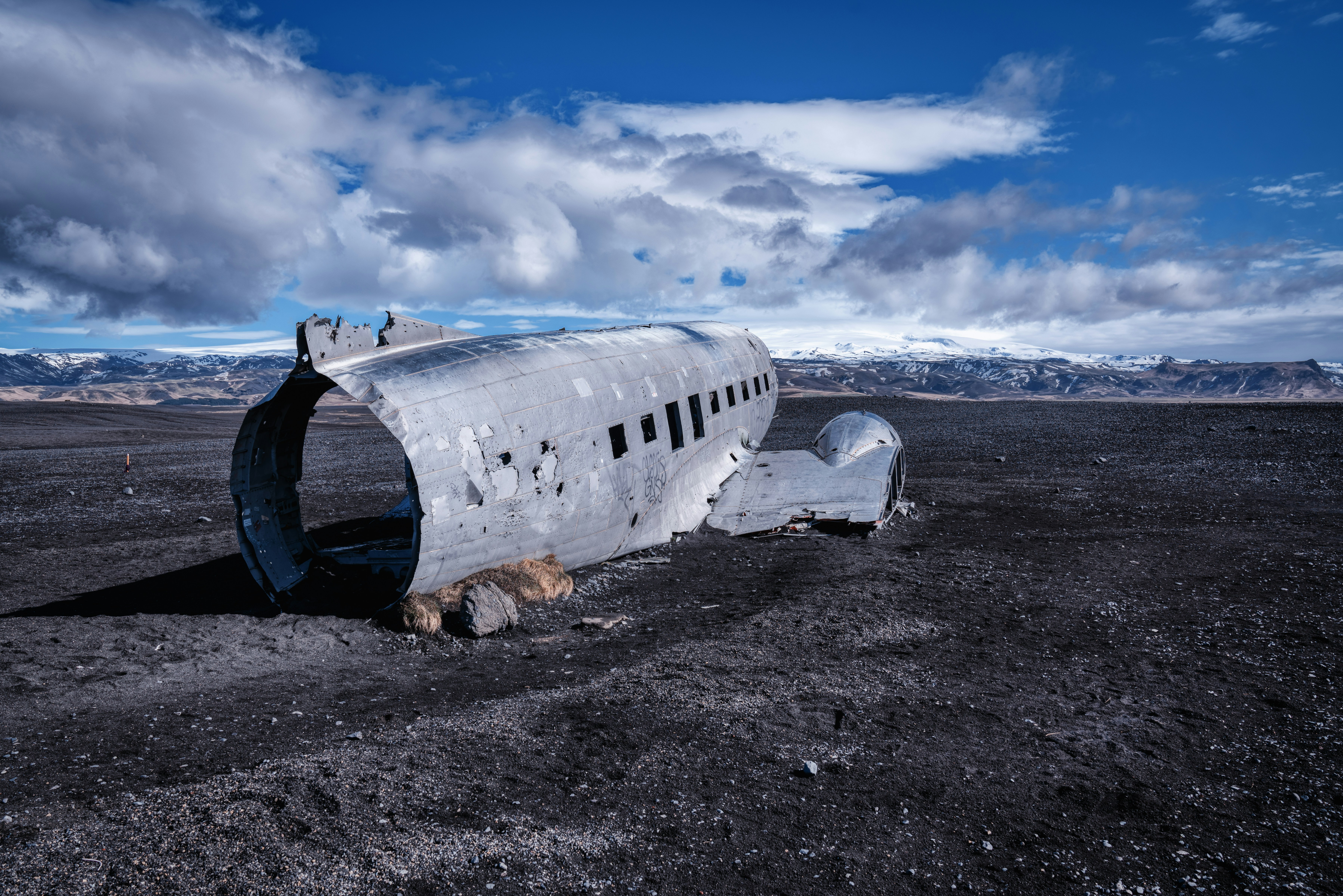 white airplane under white clouds and blue sky during daytime