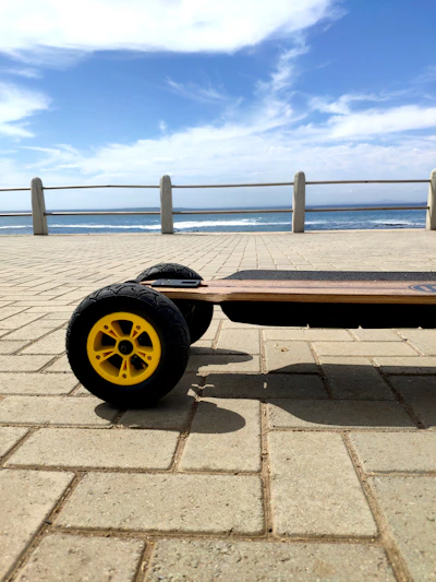 Close-up of a rider's feet on a vibrant electric skateboard with water reflections in the background.