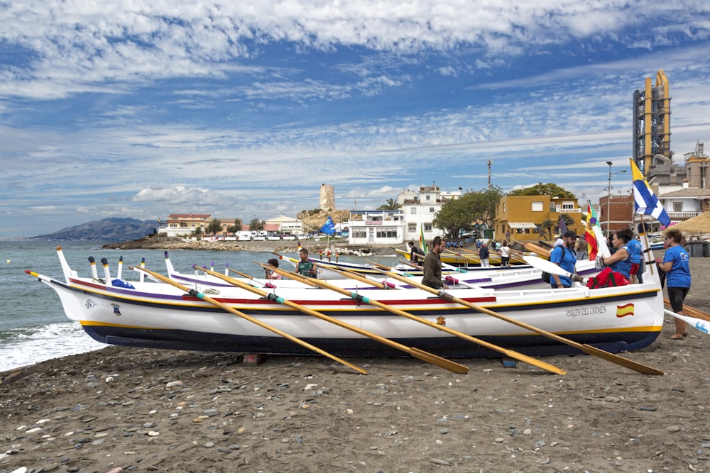 Barco blanco y rojo en la orilla del mar durante el día