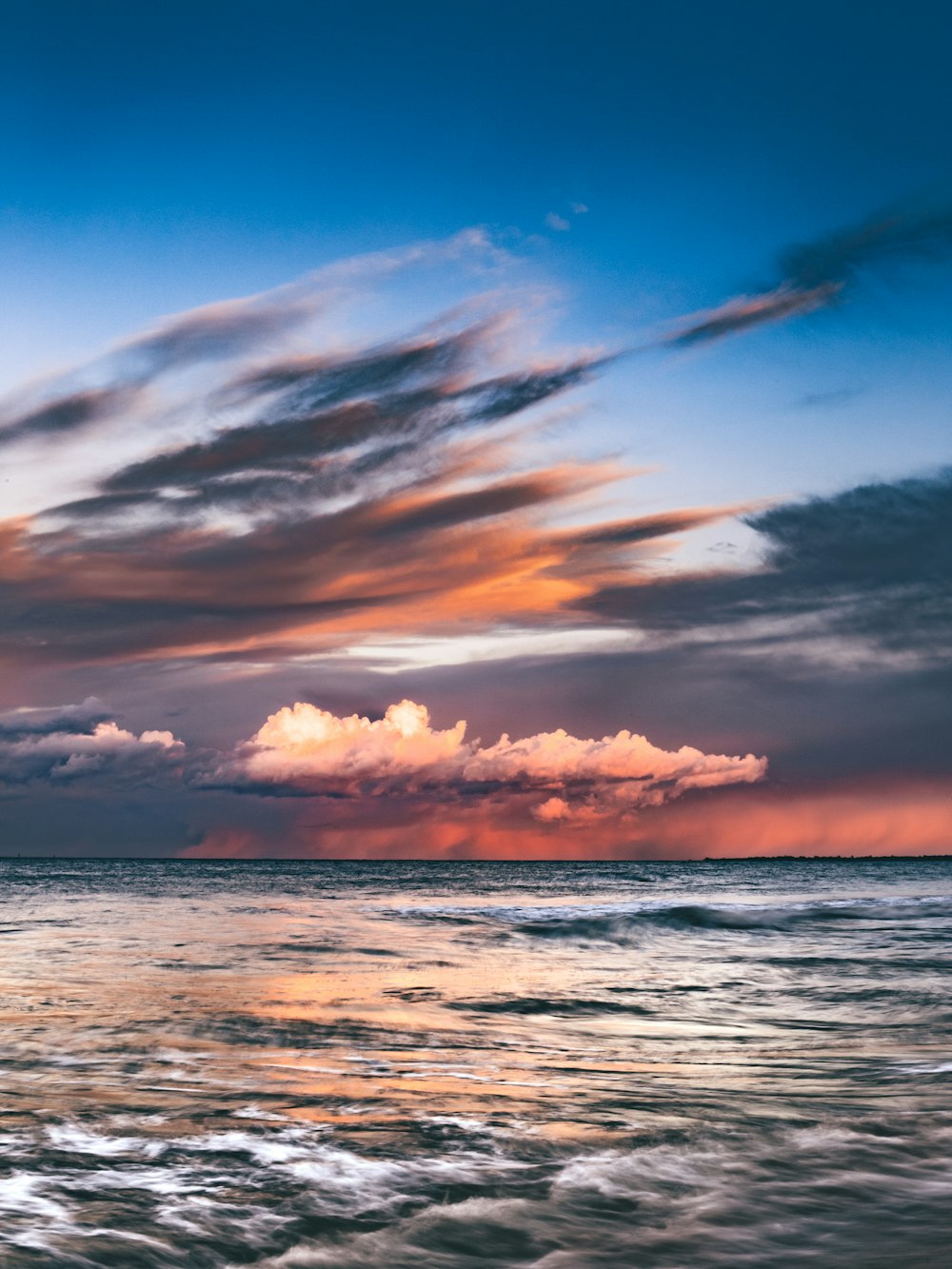 body of water under cloudy sky during sunset