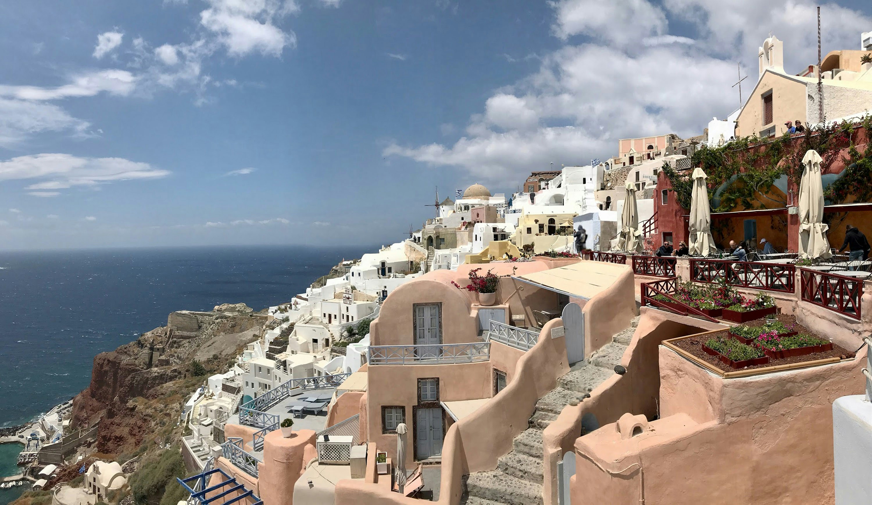 brown and white concrete houses near sea under blue sky during daytime, Cliffside houses and hotels in Santorini, Greece. 