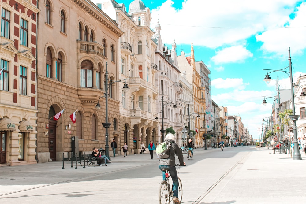 man in green jacket riding bicycle on road during daytime