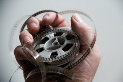 Close-up of hands holding a film reel against a dark, blurred background evoking nostalgia.
