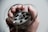 A hand is holding a roll of old-fashioned film tape with the film loosely wrapped around the fingers. The background is blurred and neutral, highlighting the focus on the film and hand.