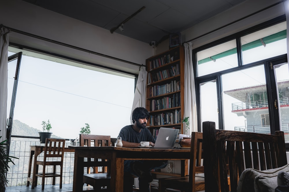 man in black jacket sitting on chair using macbook