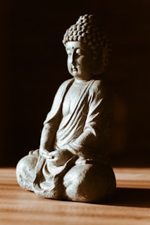 gray concrete buddha statue on brown wooden table