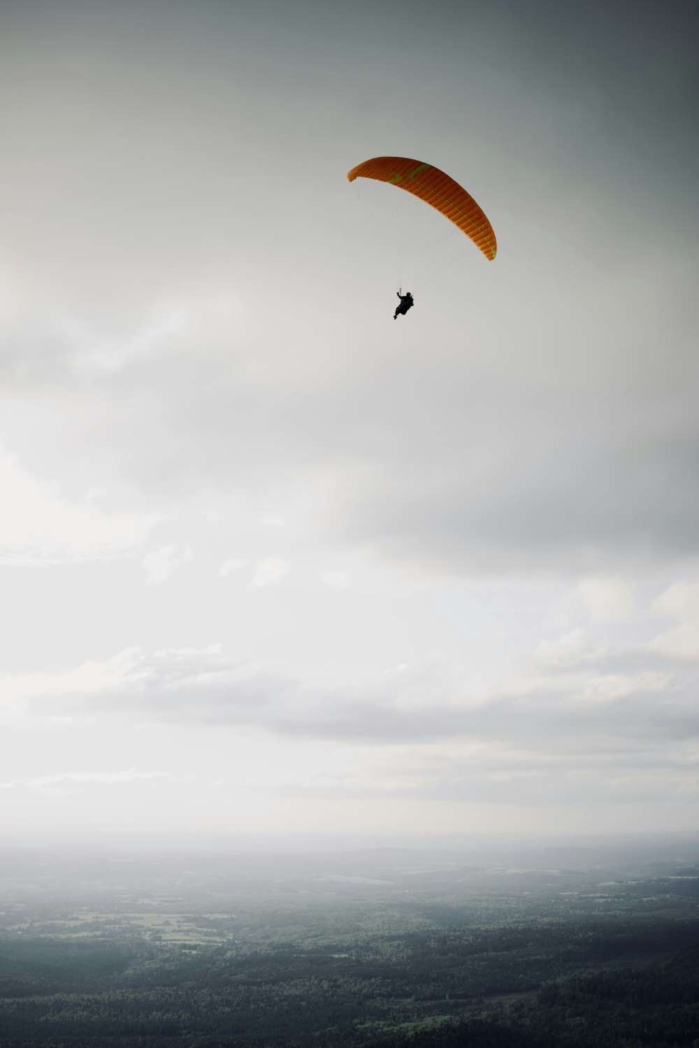 pessoa em paraquedas sob o céu nublado durante o dia