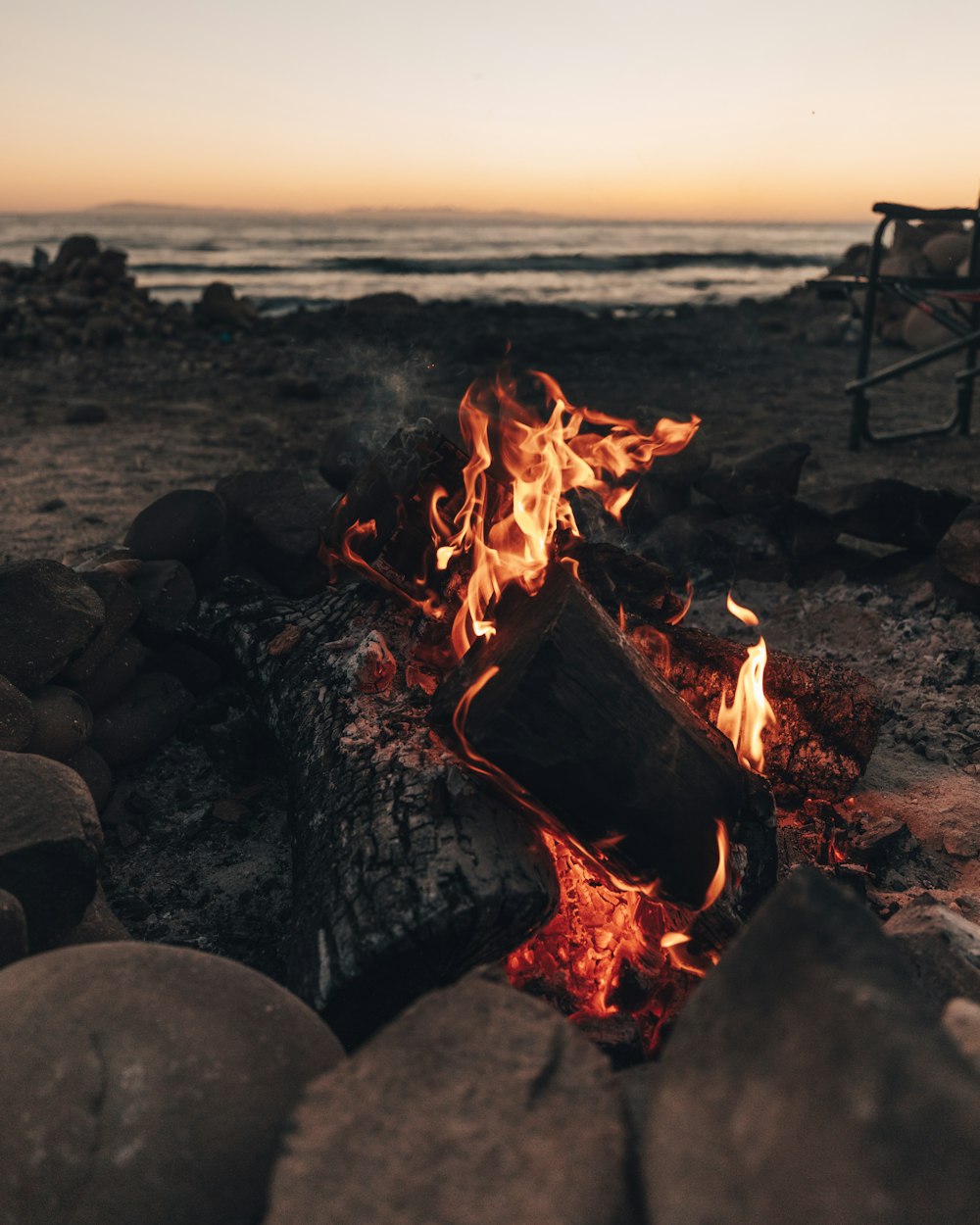 burning wood on the beach during sunset
