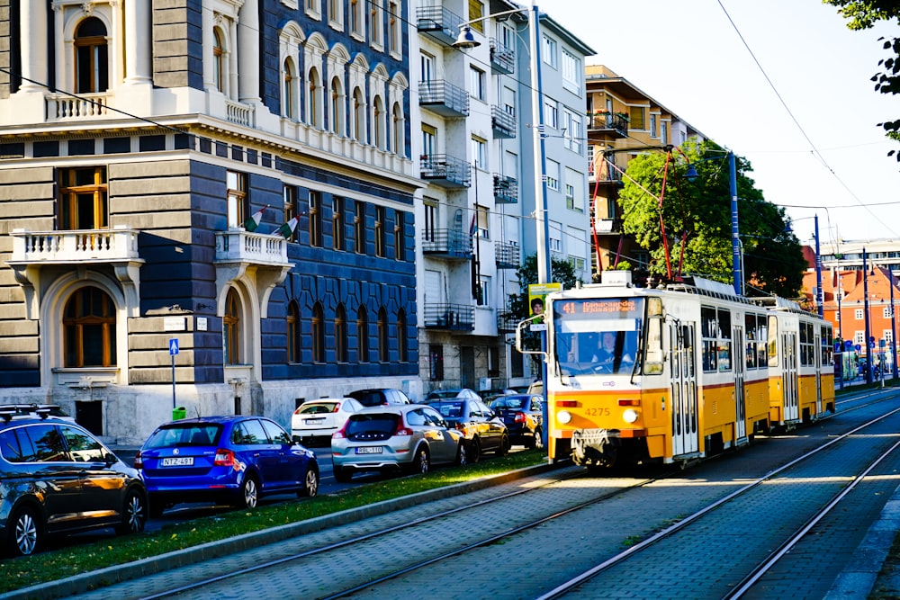 yellow and red tram on road near white concrete building during daytime