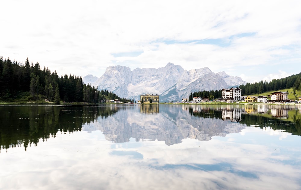 body of water near trees and mountain under white clouds during daytime