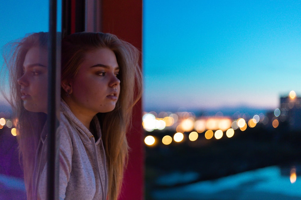 woman in gray hoodie standing near red and blue wall during daytime